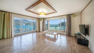 a living room with a television and large windows at tongyeong haegando pension in Tongyeong