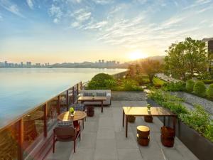 a balcony with tables and chairs and a view of the water at 珠海凤凰湾悦榕庄 in Zhuhai