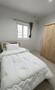 a large white bed in a room with a window at Phimpakan guesthouse in Nakhon Phanom