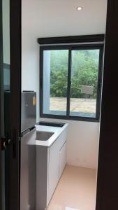 eine Küche mit Fenster und weißer Spüle in der Unterkunft Utopia Central in Ban Nong Chaeng