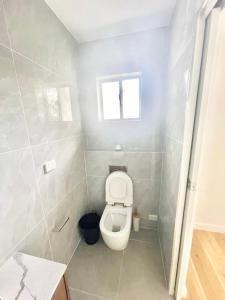 een kleine badkamer met toilet en raam bij Bedroom with Ensuite Near Train Station and Airport in Revesby