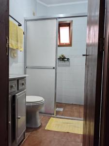 ein Badezimmer mit Toilette und Glasduschtür in der Unterkunft Aconchegante apto em Capao da Canoa in Capão da Canoa + 1 Foto
