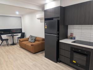 a kitchen with a refrigerator and a couch in a room at Munibung Apartments in Cardiff
