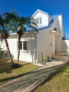 a white house with palm trees in front of it at Duplex Atypique et Authentique in Saint Martin