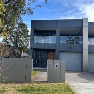 een modern huis met een poort en een garage bij Bedroom with Ensuite Near Train Station and Airport in Revesby