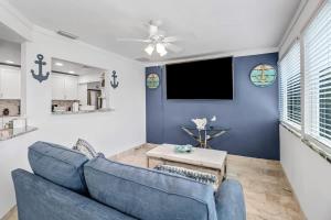 a living room with a blue couch and a tv at Elegant 4BR Waterfront Retreat l Private Pool in Marco Island