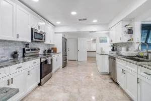 a large white kitchen with white cabinets and appliances at Elegant 4BR Waterfront Retreat l Private Pool in Marco Island