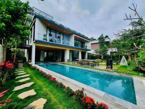 a house with a swimming pool in front of it at FLAMIGO Đại Lải - Villa Tự Doanh in Phúc Yên