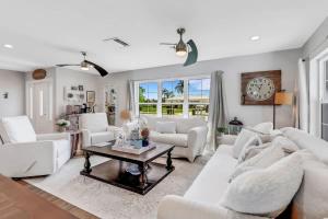 a living room with white furniture and a clock on the wall at Inviting Lakeview Home l Pool l Close to Beaches in Marco Island