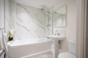 a white bathroom with a white tub and a sink at Stylish 1BR Apt near Cardiff Castle in Cardiff
