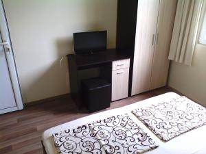 a bedroom with a bed and a desk with a television at Bungalows St. Nicola in Ahtopol
