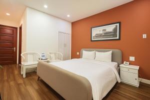 een slaapkamer met een groot bed met een oranje muur bij Saigon Central Hotel in Ho Chi Minh-stad