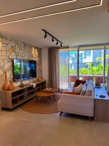 a living room with a couch and a tv at MHV Milagres - Naluum G04, Casa em condomínio beira mar de alto padrão, a poucos metros da Capela dos Milagres in Passo de Camarajibe