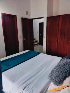 a bedroom with a large white bed with wooden cabinets at Roomiie Hostel in Villa de Leyva