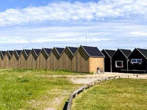 a row of buildings in a field next to a fence at 6 person holiday home in Hadsund in Hadsund +43 photos