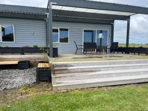 una casa con terrazza in legno e patio di The Blue Bach a Opunake