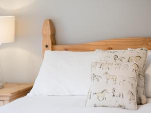 a bed with a pillow with horses on it at Hudson Cottage - Uk38152 in Newton +7 photos