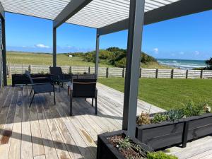 una terrazza in legno con tavolo e sedie sulla spiaggia di The Blue Bach a Opunake