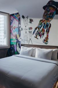 ジャカルタにあるARTOTEL Thamrin Jakartaの壁に絵が飾られたベッドのある寝室