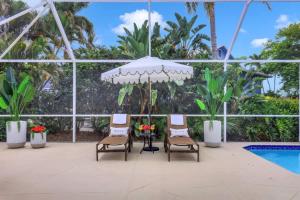 een terras met stoelen en een parasol en een zwembad bij Marco Beach House l Private Pool in Marco Island