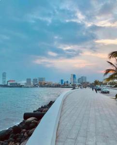 einen Bürgersteig neben einem Wasserkörper mit einer Stadt in der Unterkunft Brisa Marina Suites - Atras de Playa regatas y Malecon in Veracruz