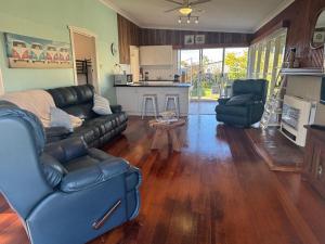 a living room with a leather couch and a table at Port Sorell Beach Shack in Port Sorell +7 photos