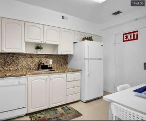 a kitchen with white cabinets and a white refrigerator at Oceanfront Penthouse with Intercoastal Views in Hollywood Beach