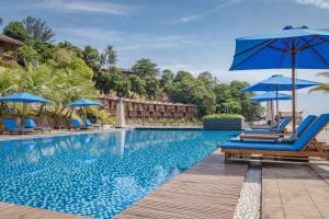 a pool at a resort with blue chairs and umbrellas at KTM Resort Batam in Sekupang