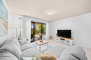 een woonkamer met een bank en een tv bij Chambers River Retreat in Maroochydore