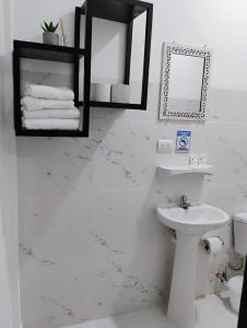 a white bathroom with a sink and a toilet at Hosteria La Veleta, Playas in Playas