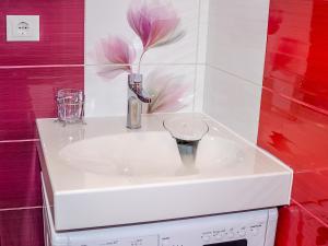 a white sink in a bathroom with a flower on the wall at Neliusi in Ventspils