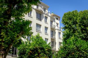 a tall white building with windows and trees at Granada Luxury Apartments in Granada