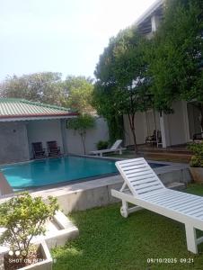 une piscine dans un jardin avec une chaise et un surveillant dans l'établissement The Ritz Hikkaduwa, à Hikkaduwa