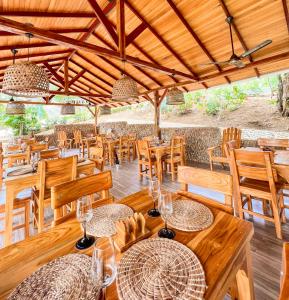 a restaurant with wooden tables and chairs with glasses on them at Ecohotel Summer Usiacuri in Usiacurí