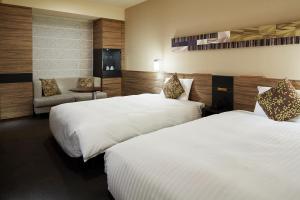 a hotel room with two beds and a chair at Mitsui Garden Hotel Sapporo in Sapporo