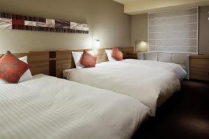two beds in a hotel room with white sheets at Mitsui Garden Hotel Sapporo in Sapporo