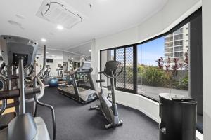 einen Fitnessraum mit Laufbändern und einem großen Fenster in der Unterkunft Seaside Solace at Caloundra Seaview 3BD Apartment in Caloundra