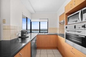 eine Küche mit Spüle und Herd oberen Backofen in der Unterkunft Seaside Solace at Caloundra Seaview 3BD Apartment in Caloundra