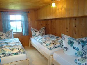 2 Betten in einem Zimmer mit Holzwänden und einem Fenster in der Unterkunft UNSER VORSÄSS - Klausberg in Schwarzenberg im Bregenzerwald