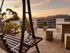 a bench on a balcony with a sunset in the background at The Budget White House Hotel in Nuwara Eliya