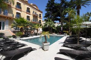 einen Pool mit Liegestühlen und ein Gebäude in der Unterkunft GOLDEN TULIP CANNES HOTEL de PARIS in Cannes