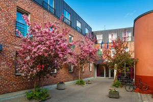 two trees in front of a brick building with pink flowers at Bern Boutique Hotel in Tallinn
