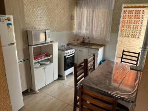 eine kleine Küche mit Tisch und Mikrowelle in der Unterkunft Sarau's Beach House Boracéia in Boracéia