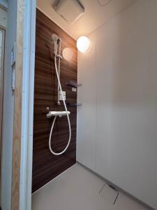 a shower in a bathroom with a wooden wall at Forest and Stars Akakura Sauna in Myoko