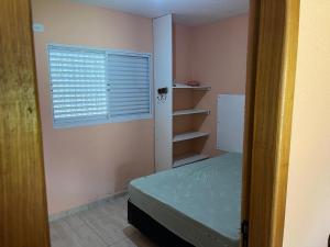 ein kleines Schlafzimmer mit einem Bett und einem Fenster in der Unterkunft Sarau's Beach House Boracéia in Boracéia + 6 Fotos