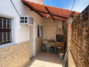 eine Terrasse mit einer Ziegelmauer und einem Dach in der Unterkunft Sarau's Beach House Boracéia in Boracéia