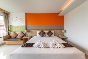 - une chambre avec un grand lit blanc et un mur orange dans l'établissement Arawana Regency South Pattaya, à Pattaya (sud)