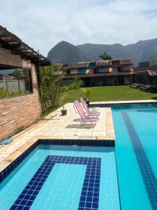 einen Pool mit zwei Liegestühlen neben einem Haus in der Unterkunft Sarau's Beach House Boracéia in Boracéia