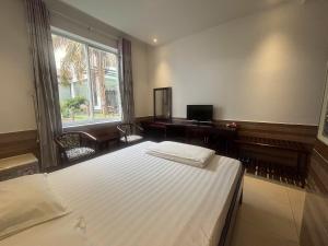a bedroom with a bed and a desk and a window at Hoang Cung Hotel in Ấp Phú Thọ +25 photos