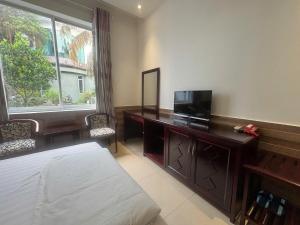a bedroom with a desk with a television and a mirror at Hoang Cung Hotel in Ấp Phú Thọ